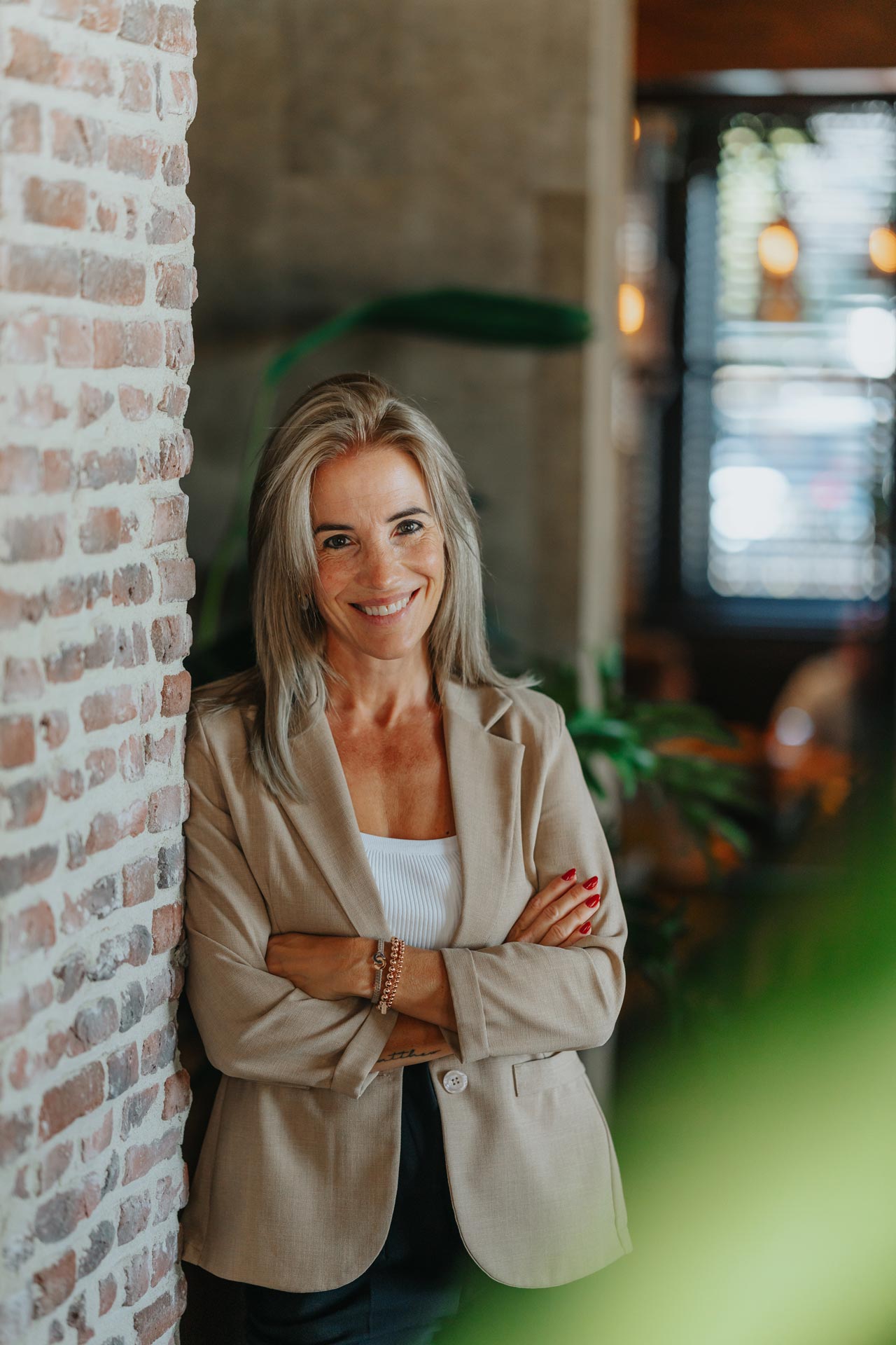 Portret van Babette van Creatic Digital Agency in een beige blazer tegen een bakstenen muur